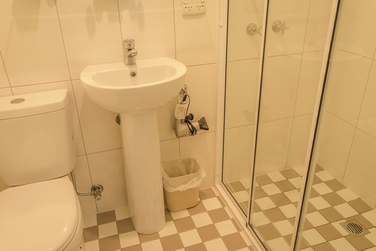 A bathroom with a toilet, sink, and glass shower enclosure.