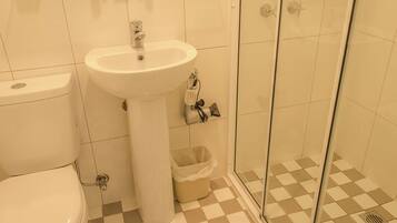 A bathroom with a toilet, sink, and glass shower enclosure.