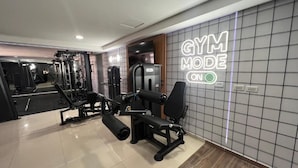 Un gimnasio con máquinas de pesas, un espejo y un letrero de neón en la pared.