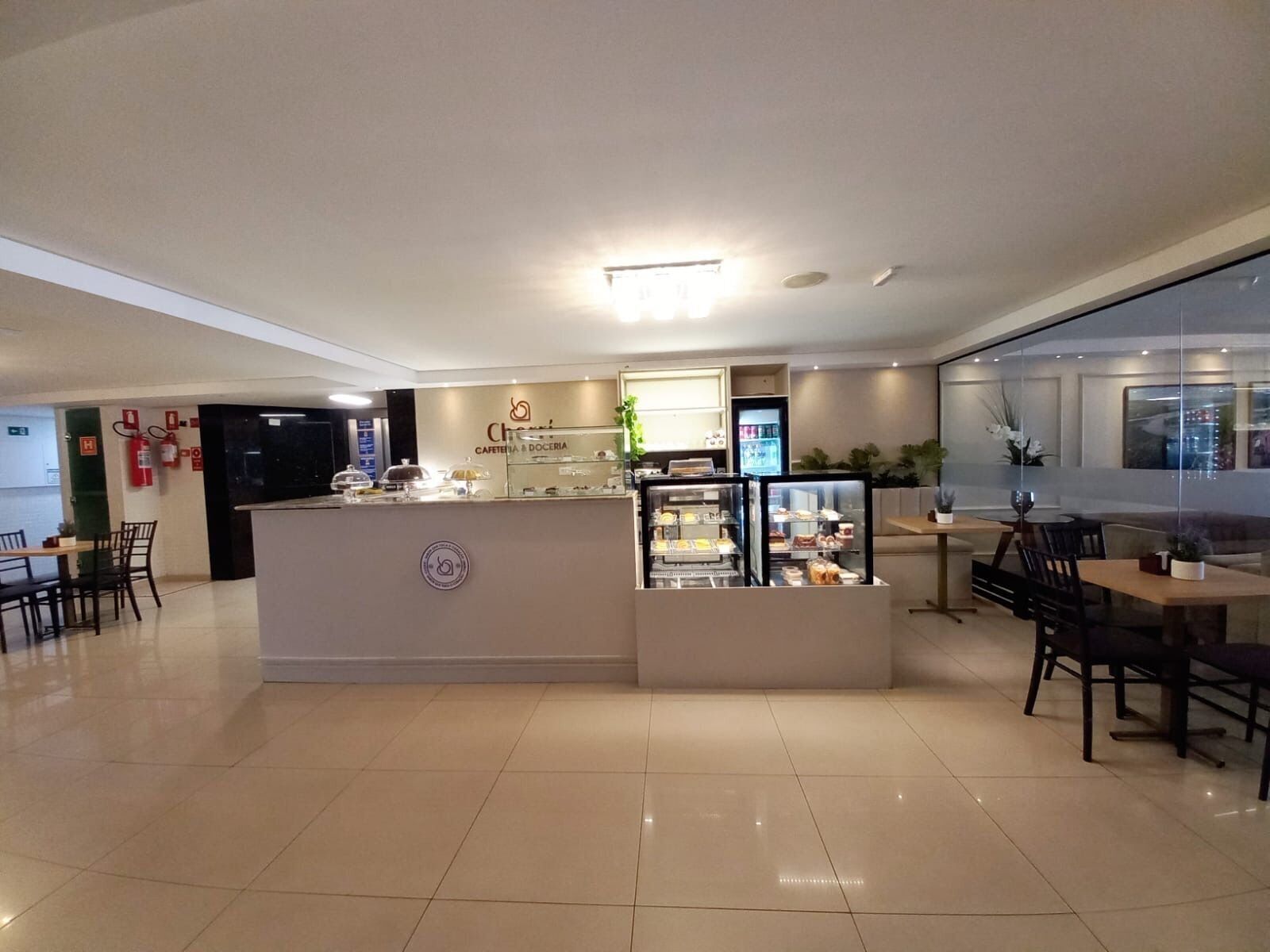 Una cafetería con mostrador, zona de estar y un extintor en la pared.