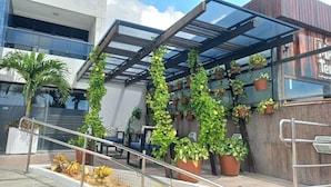 Un edificio moderno con fachada de vidrio, zona de estar al aire libre y plantas en macetas.