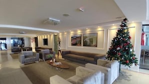 Un amplio salón con un sofá grande, sillones y una mesa de centro. Se ve un árbol de Navidad en la esquina.