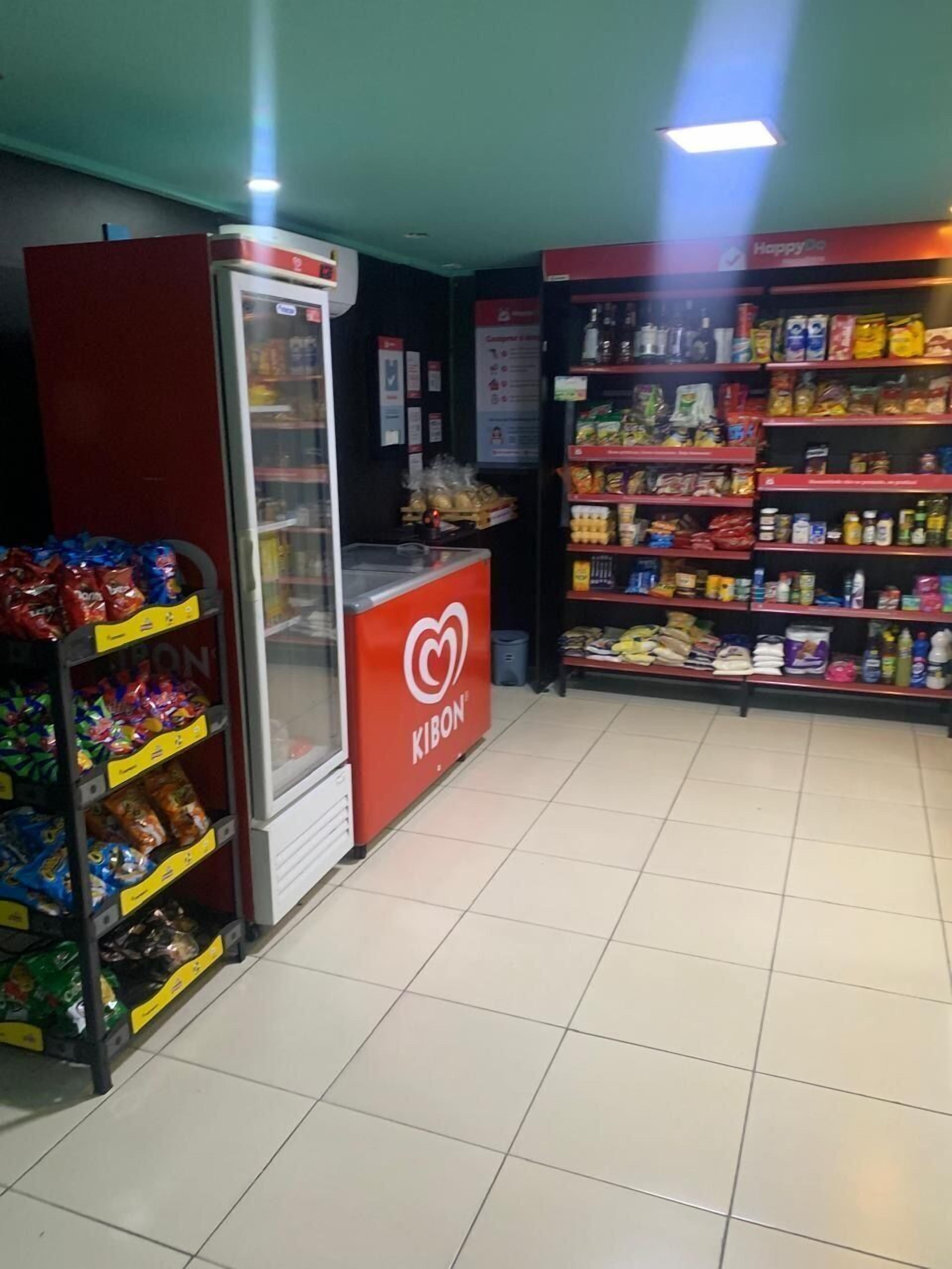 A KIBON store with a refrigerated display, shelves stocked with snacks, and a checkout counter.