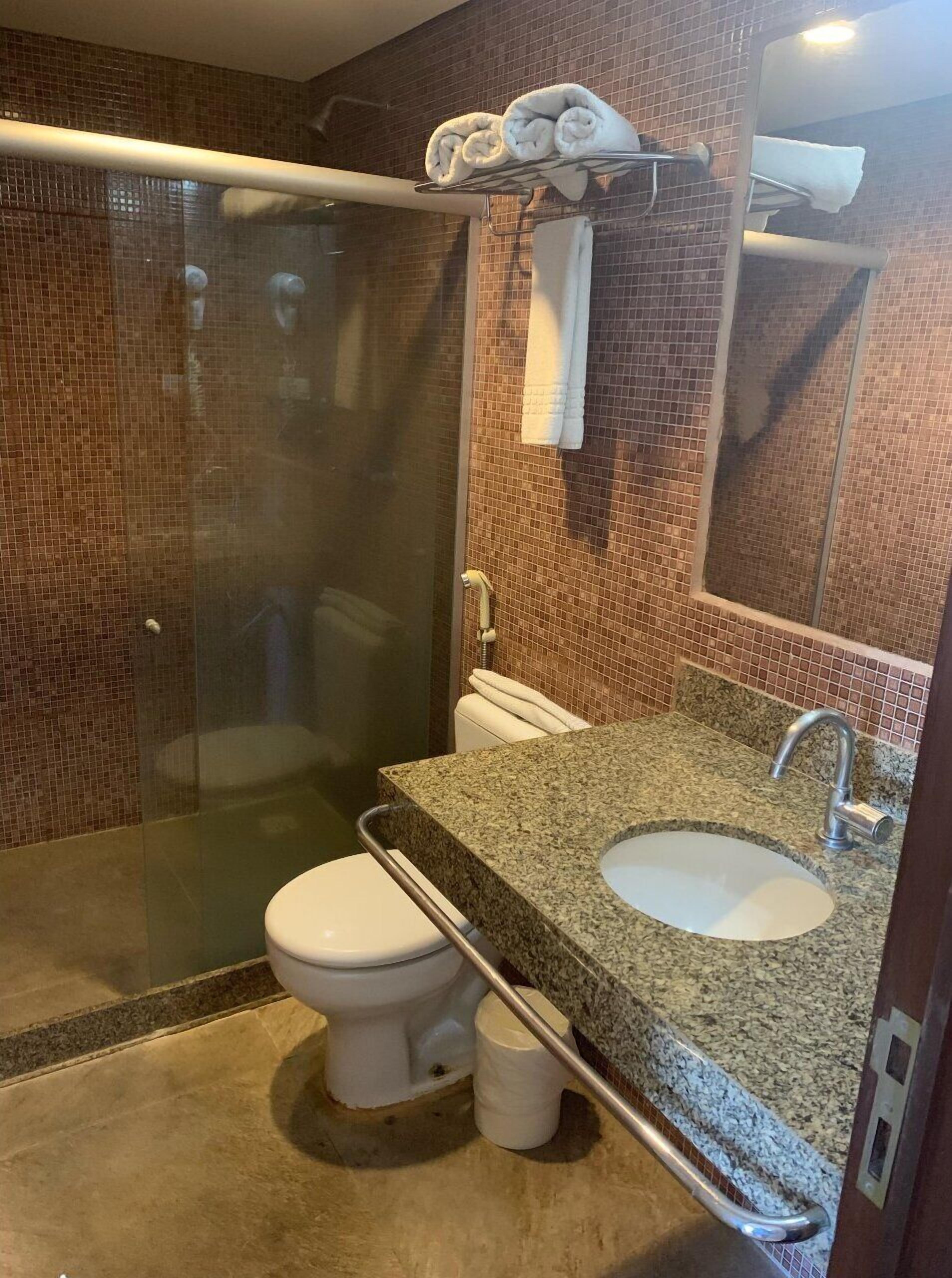 Un bagno con doccia vetrata, un water bianco e un lavabo con piano in granito.