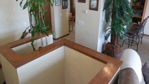 Amplia sala de estar con una mesa de centro de madera, una planta grande en maceta y un comedor con una silla y una mesa.