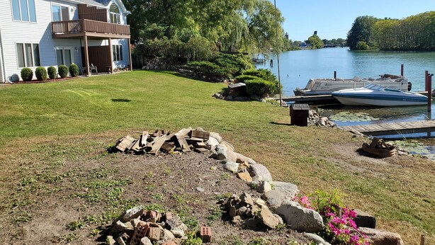 Una propiedad frente al lago con una casa, muelle y un bote amarrado.