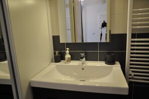 Bathroom features a sink, mirror, and black and white tiles.