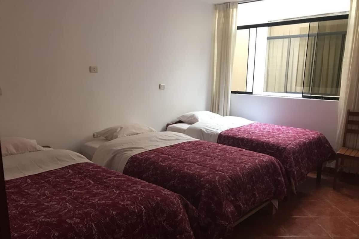 A room with three beds, each with a different bedspread.