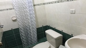 A bathroom with a toilet, sink, and shower area. - Hospedaje Las Flores (Trujillo)