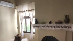 Una habitación con una mesa, una olla, un florero y una chimenea.
