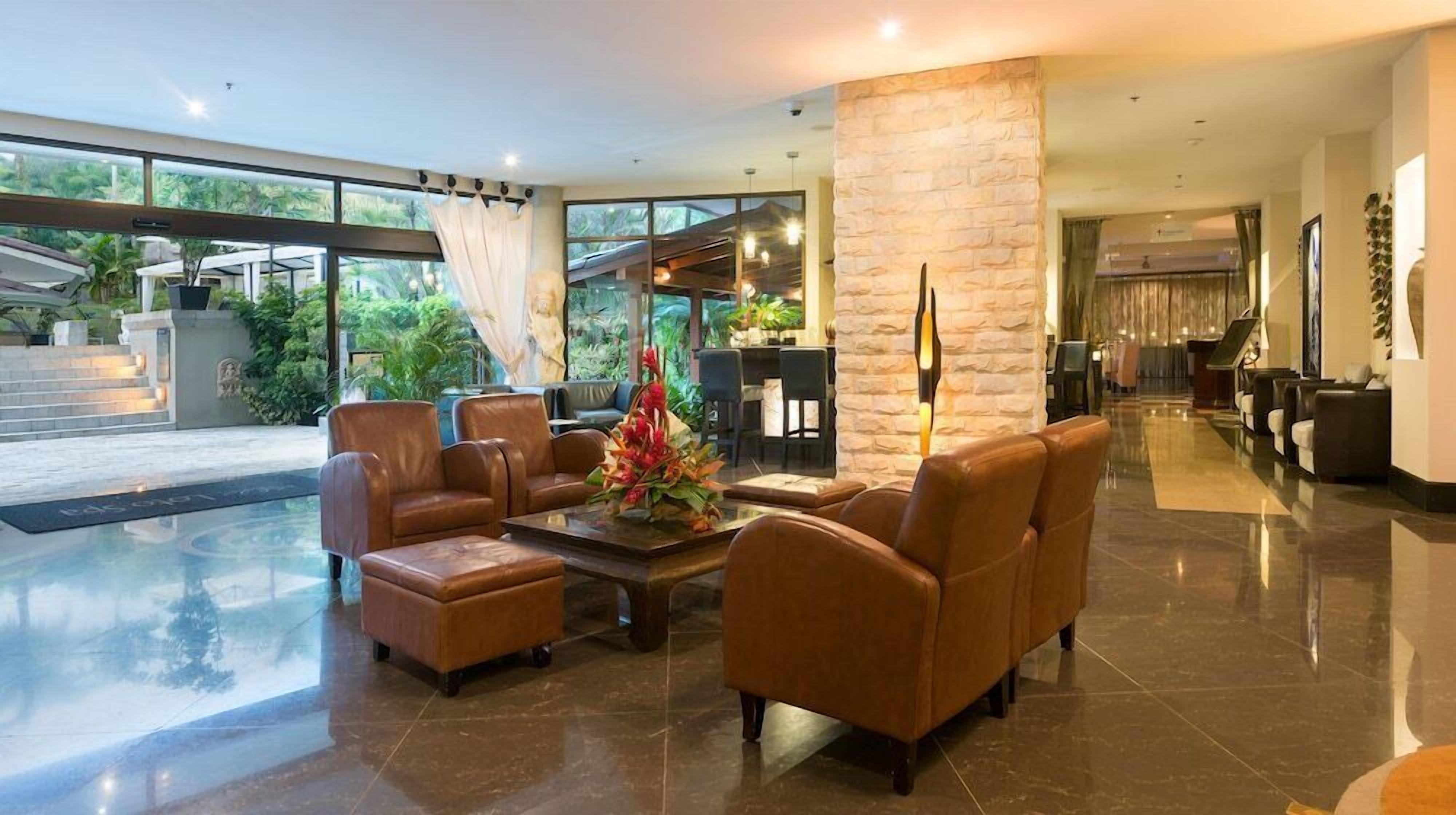 A lobby with leather sofas, a coffee table, a stone pillar, and a reception desk.
