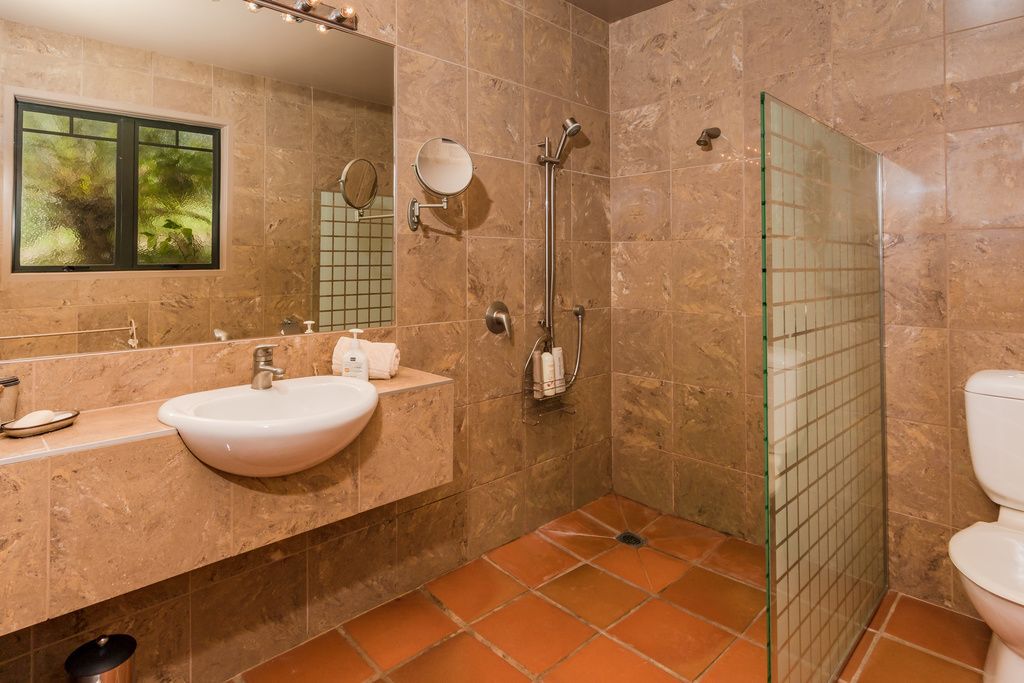 A bathroom with a sink, mirror, and shower.