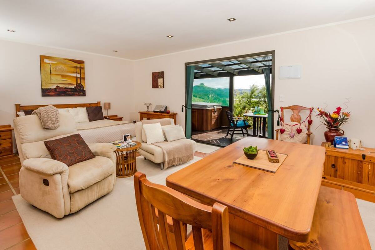 A spacious living area with a sofa, a dining table, and a view of the outdoors.