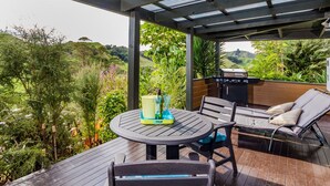 An outdoor patio with a round table, two chairs, a grill, and a lounge chair.