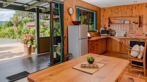 A wooden interior with a kitchen, a dining area, and a sliding glass door leading to a patio.
