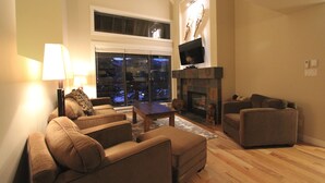 A living room with a fireplace, two sofas, a coffee table, and a TV mounted on the wall. - Villas Snowberry by Whistler Retreats (Whistler)