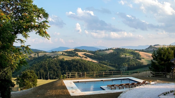 A pool area with a view of rolling hills and a distant mountain range. - La Cerqua (Arcevia)