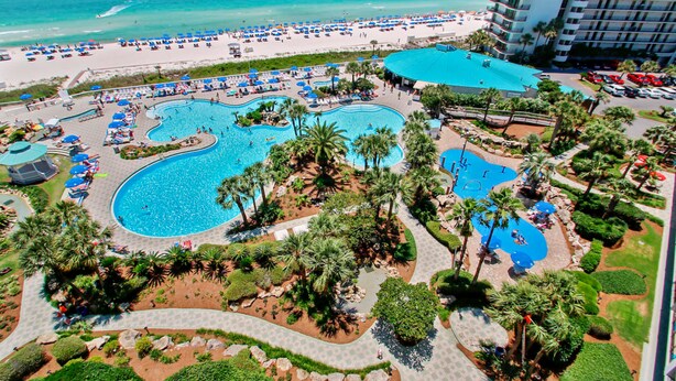 Um resort com várias piscinas, uma praia e um grande edifício de hotel.