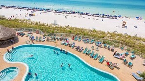 Una piscina con sillones de descanso y una playa al fondo.