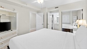 Una habitación de hotel con una cama, un televisor en una cómoda, un ventilador de techo y un espejo.
