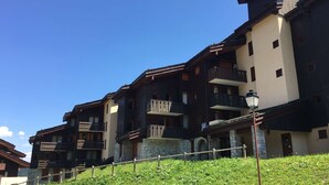 Un hôtel à plusieurs étages doté de balcons, d’une façade en pierre et surplombant un ciel d’un bleu limpide.