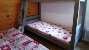 Ein Etagenbett mit einer Leiter, einer gesteppten Bettdecke und einer Holzwand.