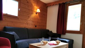 Un intérieur en bois avec un canapé, une table avec des verres à vin et une lampe.
