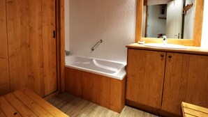 Ein Badezimmer aus Holz mit einer Badewanne, Holzschränken und einem Spiegel.