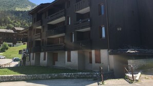 Ein mehrstöckiges Gebäude mit Balkonen, einer Steinwand und einem Berg im Hintergrund.