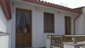 A small building with a tiled patio, wooden doors, and windows. - Casa Mannu Fluminimaggiore - Authentic home in the historic village center (Fluminimaggiore)