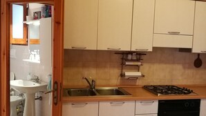 A kitchen with white cabinets, a sink, a stove, and a dishwasher. - Casa Mannu Fluminimaggiore - Authentic home in the historic village center (Fluminimaggiore)