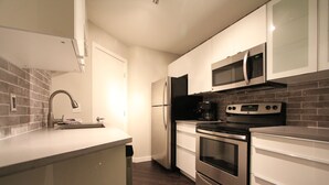 A modern kitchen with white cabinets, stainless steel appliances, and a tiled backsplash.