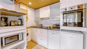 A modern kitchen with white cabinetry, a built-in oven, a dishwasher, and a coffee maker. - Grand Roc C322 280m from Slopes, Parking & WiFi, Argentière (Chamonix), France (Argentière (Chamonix))