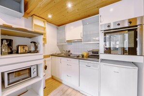 A modern kitchen with white cabinetry, a built-in oven, a dishwasher, and a coffee maker. - Grand Roc C322 280m from Slopes, Parking & WiFi, Argentière (Chamonix), France (Argentière (Chamonix))