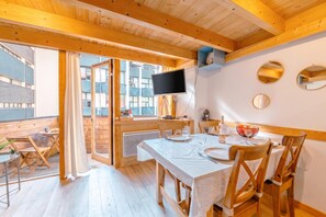 A wooden interior with a dining area, a TV mounted on the wall, and a view through the glass door. - Grand Roc C322 280m from Slopes, Parking & WiFi, Argentière (Chamonix), France (Argentière (Chamonix))