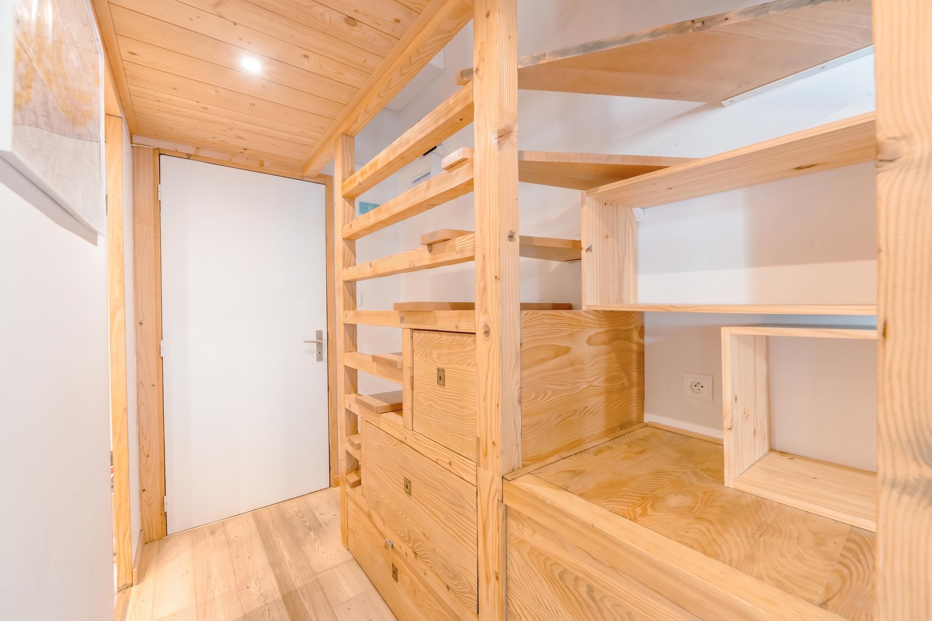 Een houten interieur met inbouwplanken en een witte deur.