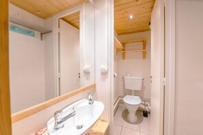 Une salle de bain avec un lavabo blanc, un miroir et des toilettes.
