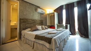 A hotel room with a large bed, a wardrobe, a mirror, and an air conditioning unit. - Beira Mar Hotel (Aracaju)