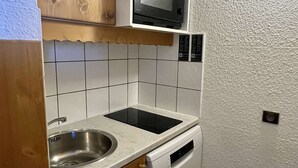 Una cocina compacta con armarios de madera, un microondas, un lavavajillas y un fregadero.
