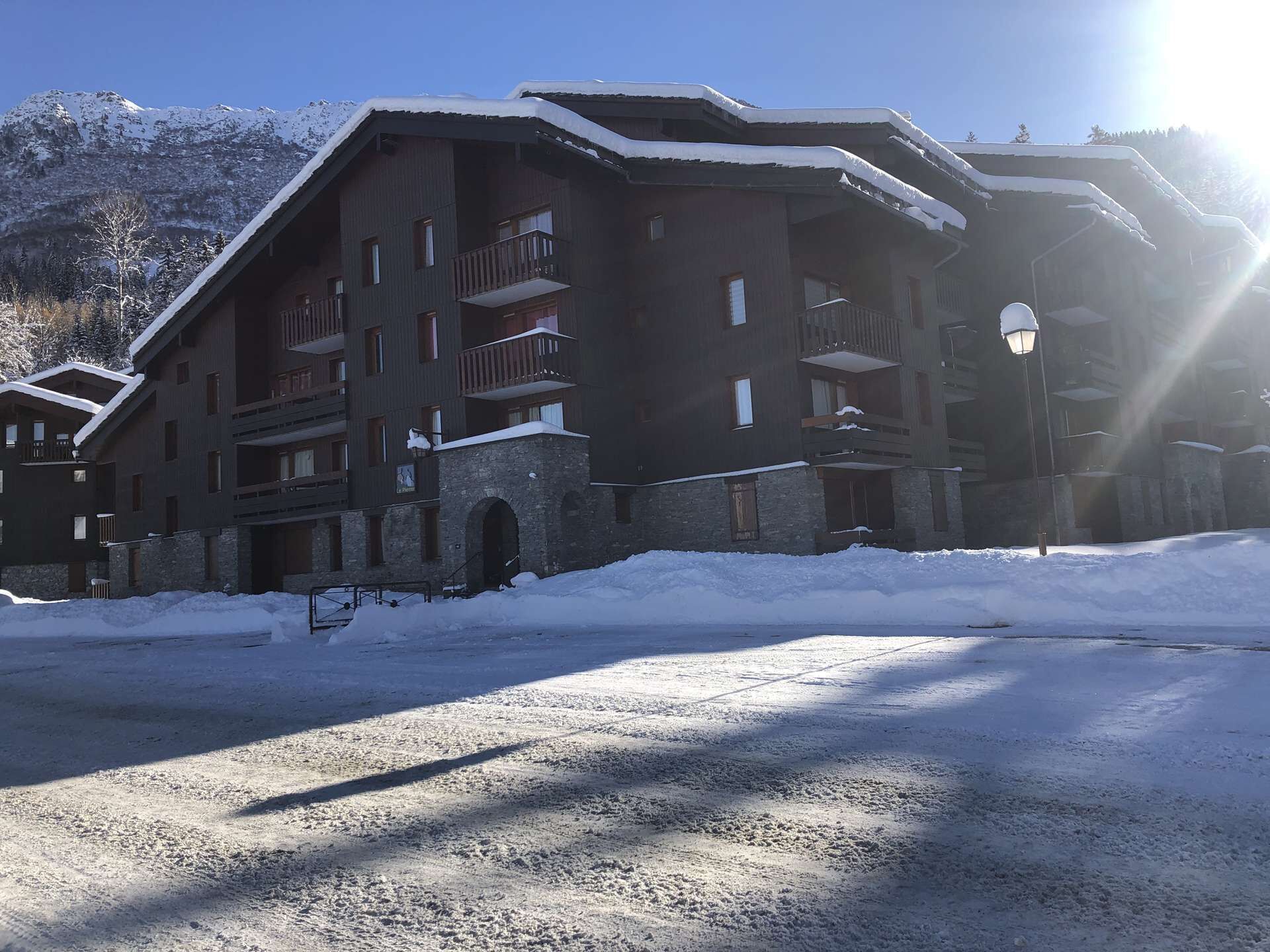 Uma pousada de vários andares com varandas e entrada de pedra, cercada por neve.