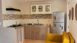 Une cuisine compacte équipée d’une cuisinière intégrée, d’un évier et d’un réfrigérateur à deux portes.