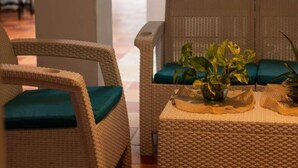 Des meubles en osier agrémentés de coussins verts et une petite table sur laquelle est posée une plante.