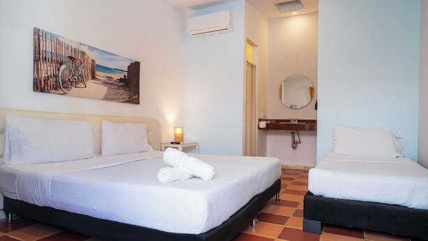 Une chambre d’hôtel avec deux lits, un tableau, un climatiseur, un miroir et un sol carrelé.