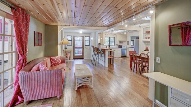 A spacious living area with a wooden ceiling, a dining area with a kitchen in the background, and a cozy seating arrangement. - Om Shanti - Murphys Vacation Rentals (Murphys)