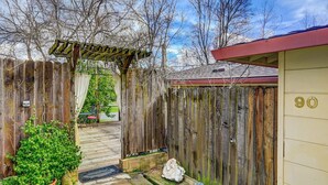 A wooden gate leading to a house with a red roof and a number '90' sign. - Om Shanti - Murphys Vacation Rentals (Murphys)