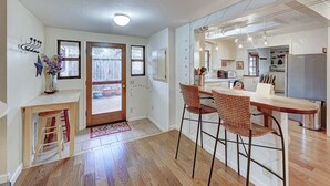 A modern kitchen with a wooden countertop, a dining area with wicker chairs, and a visible door leading to a patio. - Om Shanti - Murphys Vacation Rentals (Murphys)