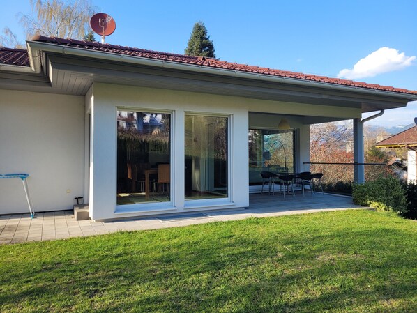 Une maison moderne dotée d’un patio couvert, de portes-fenêtres coulissantes et d’une antenne parabolique.