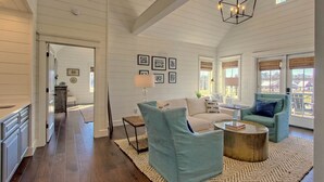 A spacious living room with a high ceiling, a dining area, and a kitchen.