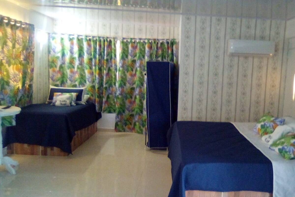 Habitación de hotel con dos camas, un armario y cortinas con estampado tropical.
