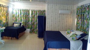A hotel room with two beds, a wardrobe, and curtains with a tropical pattern.